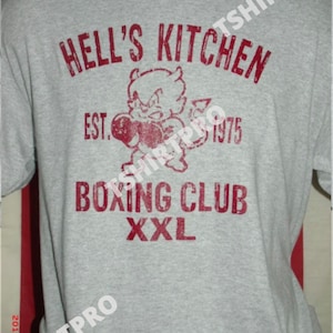 May include: A gray t-shirt with a red print that says "Hell's Kitchen Boxing Club Est. 1975 XXL". The print features a cartoon devil with boxing gloves.