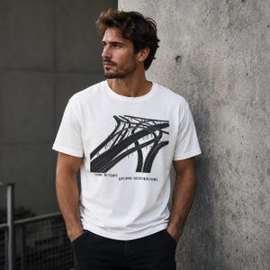 Könnte beinhalten: Ein weißes kurzärmeliges T-Shirt mit einem schwarzen Grafikdruck eines komplexen Autobahnkreuzes. Unter der Abbildung steht der Text: SOME DETOURS BECOME DESTINATIONS. Das T-Shirt hat einen Rundhalsausschnitt und eine normale Passform.