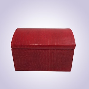 May include: A red, rectangular storage box with a curved top. The box has a textured, crocodile-like pattern. The box is a solid, vibrant red color and appears to be made of leather or a similar material. The box is empty.