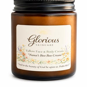 Op de afbeelding: Een bruine glazen pot met een zwart deksel, met het label "Glorious Skincare". Het label bevat tekst voor "Tallow Face & Body Cream" en "Nana's Boo Boo Cream", met een bloemenrand en een bijbelvers.