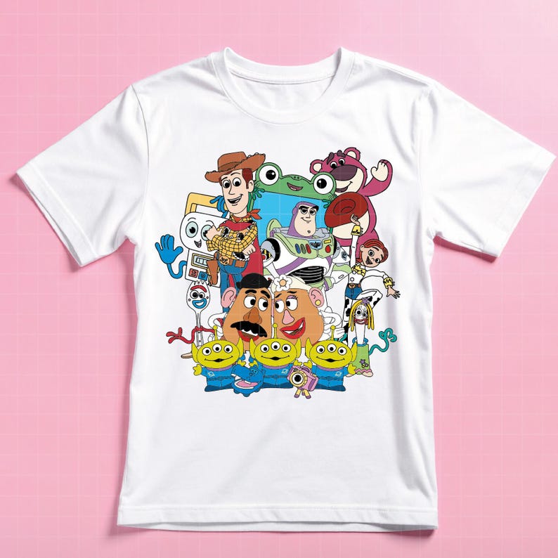 May include: White t-shirt with a vibrant graphic of Toy Story characters, including Woody, Buzz Lightyear, Mr. and Mrs. Potato Head, and the Little Green Men. The tee has a crew neck and short sleeves. The design is a colourful cartoon.
