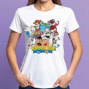 May include: White t-shirt with a vibrant graphic of Toy Story characters, including Woody, Buzz Lightyear, and the Little Green Men. The design is a colourful illustration of the animated film's characters. The t-shirt is made of a soft, lightweight fabric.