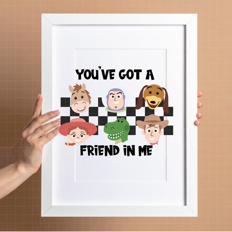 May include: A white framed print featuring a black and white checkered pattern with cartoon character faces including a horse, space ranger, dog, cowgirl, dinosaur, and cowboy. The text reads YOU'VE GOT A FRIEND IN ME in bold black letters.