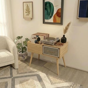 以下が含まれることがあります： レコードプレーヤー用の明るい木製のスタンド。レコード用のコンパートメントとMarshallスピーカーが付いています。スタンドは、角度の付いた脚を備えたミッドセンチュリーモダンデザインです。小さな黒い花瓶と鉢植えの植物も表示されています。
