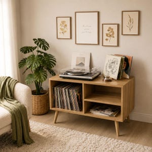 Könnte beinhalten: Ein helles Holz-Plattenspieler-Konsolenmöbel mit einer Sammlung von Schallplatten, einem Plattenspieler und gerahmten botanischen Drucken. Eine große Topfpflanze und ein Sessel mit einer grünen Decke ergänzen die Einrichtung.
