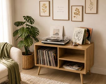 May include: A light wood record player console with a collection of vinyl records, a turntable, and framed botanical prints. A large potted plant and a cozy armchair with a green blanket complete the room's decor.