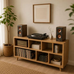 May include: A wooden entertainment center with a record player, speakers, and storage for vinyl records and other media. The speakers are dark brown with copper-colored speaker cones. A framed picture hangs on the wall above the center.