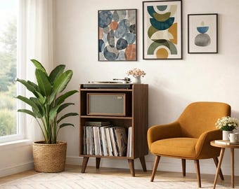 May include: A living room scene featuring a mid-century modern style. A brown wooden record player stand with a speaker and vinyl records is next to an orange armchair. Three framed abstract art pieces hang on the wall. A large potted plant sits near a window.