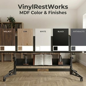 May include: A display showcasing MDF color and finishes, including Walnut, Oak, White, Black, and Anthracite. The display features a black metal stand with a shelf holding a book, a tuning fork, and a metronome. The text "VinylRestWorks MDF Color & Finishes" is at the top.