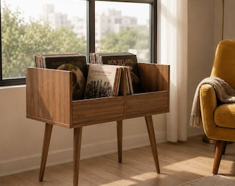 May include: A mid-century modern record storage cabinet made of wood. The cabinet has two compartments and angled legs. Several vinyl records are stored inside. The cabinet is placed near a window with a view of a city.