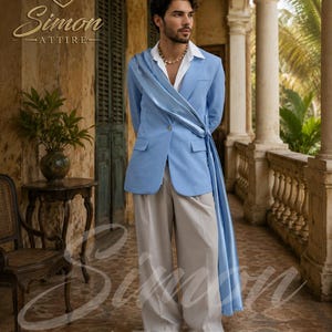 May include: A light blue blazer featuring a draped sash detail across the front, worn over a white collared shirt with beige trousers and white sneakers. The garment includes the Simon Attire logo and text on the upper left and bottom center.