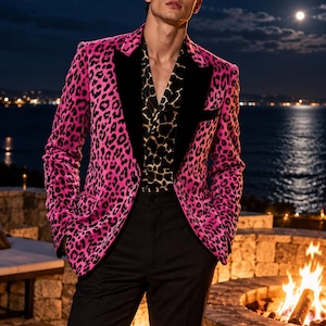 May include: A bright pink leopard print blazer with black velvet lapels, worn over a black and gold animal print shirt and black trousers. The Simon Attire logo is visible in the top left corner of the image, featuring a tuxedo icon.
