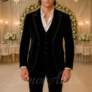 May include: A black velvet suit with a white dress shirt. The suit includes a jacket, vest, and trousers. The image features the text "Simon Attire". The background includes chandeliers and floral arrangements.