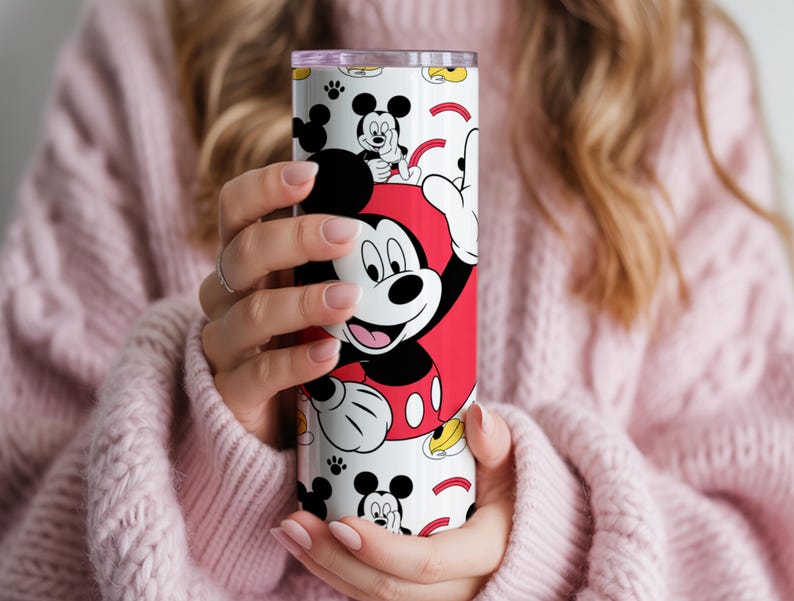 May include: A white and red tumbler featuring Mickey Mouse. The tumbler has a repeating pattern of Mickey Mouse and his iconic gloves. The tumbler is cylindrical and appears to be made of stainless steel.