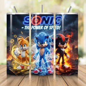 May include: A cylindrical tumbler with a lid and straw featuring a graphic print of Sonic, Tails, and Shadow. The design includes the text SONIC - THE POWER OF SPEED! with lightning, fire, and golden rings against a dark, stormy background.