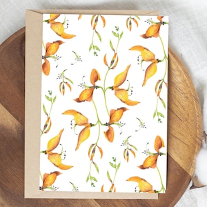 Puede incluir: Una tarjeta de felicitación con un diseño floral en acuarela. La tarjeta presenta un patrón repetido de flores naranjas y amarillas con tallos y hojas verdes sobre un fondo blanco. La tarjeta está en un sobre marrón.