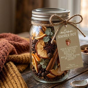 May include: A clear glass mason jar filled with dried orange slices, cinnamon sticks, star anise, and eucalyptus leaves. A tan tag tied with twine reads: autumn SIMMER POT, POUR CONTENTS INTO BOILING WATER AND REDUCE TO SIMMER, REPLENISH WATER AS NEEDED. ENJOY! Olma's HOMEMADE GOODS.