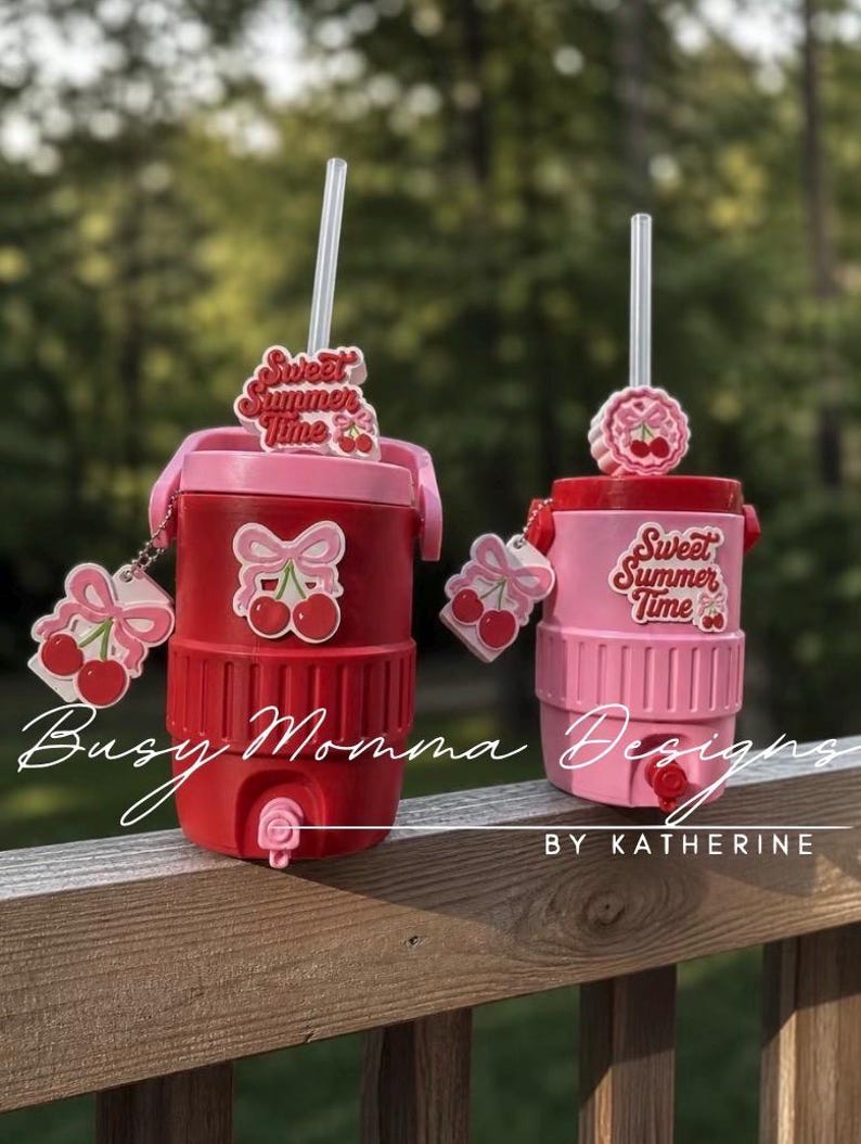 May include: Two insulated tumblers, one red and one pink, with cherry decorations. Each has a straw and a cherry charm. The text "Sweet Summer Time" is on the top of each tumbler. Ideal for summer drinks.