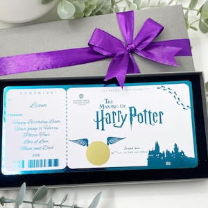 Puede incluir: Una caja de regalo gris con una cinta morada, que contiene un boleto para el tour "The Making of Harry Potter". El boleto tiene un área para rascar y el texto "Feliz Cumpleaños Liam".