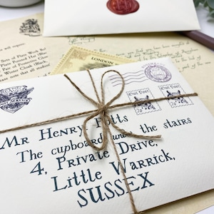 Op de afbeelding: Crèmekleurige envelop, vastgebonden met touw, geadresseerd aan Mr. Henry Potts, met "Owl Post" postzegels en een zegel. De briefpapierset bevat een brief met een poststempel uit Londen.