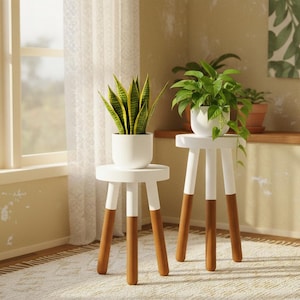 May include: Two small, white plant stands with wooden legs, each supporting a potted plant. One stand holds a snake plant, the other a pothos. The stands have a modern, minimalist design, perfect for indoor decor.