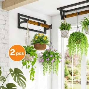 May include: Two black metal and wood hanging plant racks with multiple hanging planters filled with various green and flowering plants. The planters are suspended by rope and macrame hangers. The image includes a white brick wall and a window.