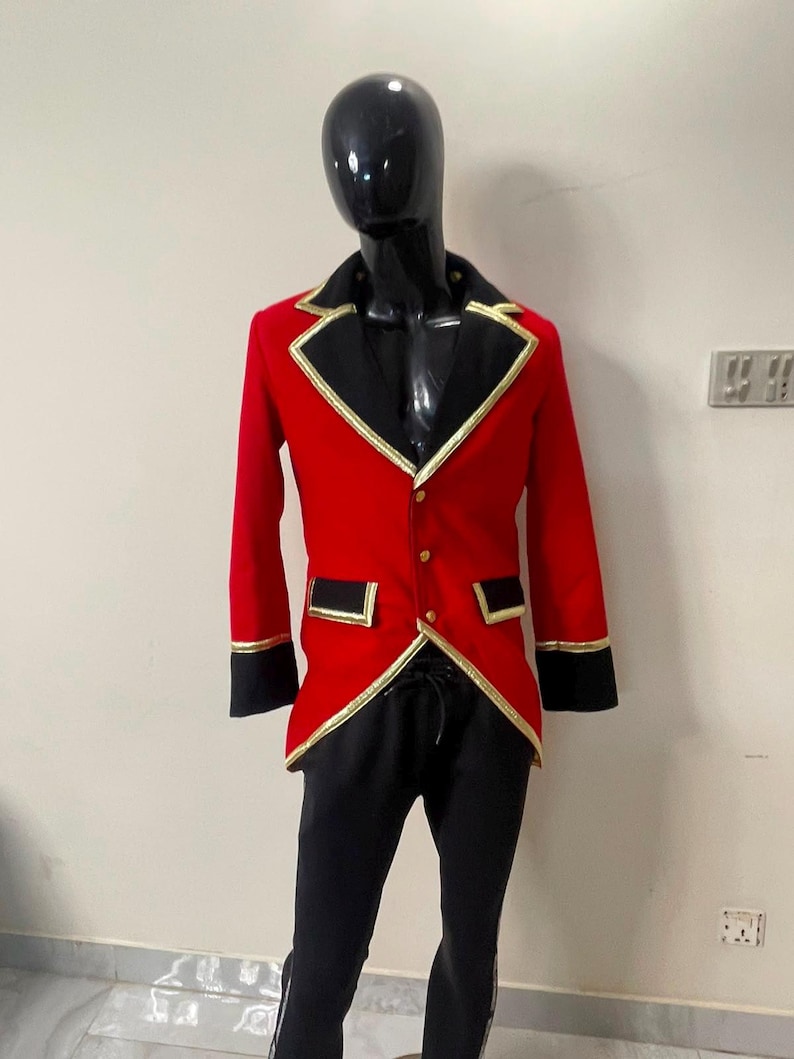 May include: A red jacket with black lapels, black cuffs, and gold trim, featuring three gold buttons down the front and two flap pockets. The jacket is paired with black trousers, displayed on a glossy black mannequin torso.