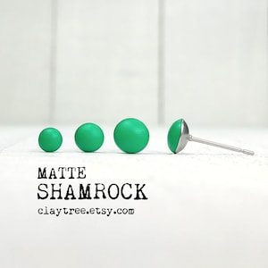 May include: Matte green shamrock stud earrings. The earrings are shown in different sizes. The text "MATTE SHAMROCK claytree.etsy.com" is below the earrings.