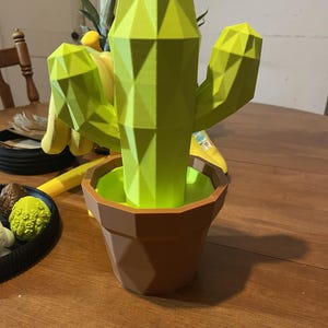 May include: A white ceramic mug with a black handle and the text "But First, Coffee" in a black, handwritten-style font. The mug is on a white surface.