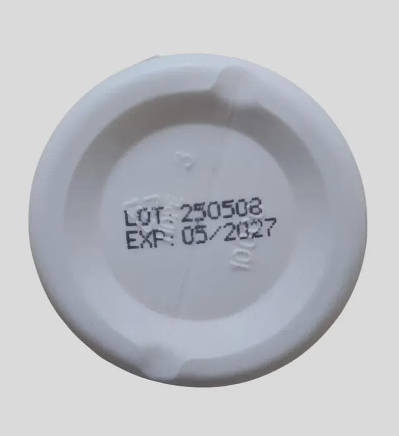 K&ouml;nnte beinhalten: Ein wei&szlig;er Kunststoff-Flaschenverschluss mit dem Text "LOT: 250508" und "EXP: 05/2027" in Schwarz aufgedruckt. Der Verschluss hat ein kreisf&ouml;rmiges Design mit leicht erh&ouml;htem Rand und einer kleinen Vertiefung.