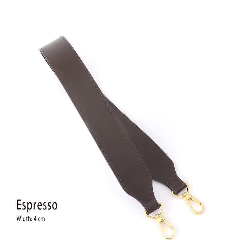 May include: Espresso-colored bag strap with gold-tone clasps. The strap is made of a smooth material and is 4 cm wide. The strap is designed to be attached to a bag.