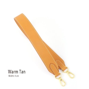 May include: A warm tan leather bag strap with gold-colored metal clasps. The strap is 4 cm wide and features white stitching along the edges. The text "Warm Tan" is displayed on the image.