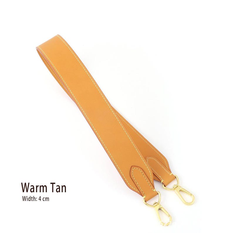 May include: A warm tan leather bag strap with gold-colored metal clasps. The strap is 4 cm wide and features white stitching along the edges. The text "Warm Tan" is displayed on the image.