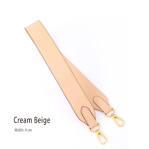 May include: Cream beige purse strap with gold-colored metal clasps. The strap is 4 cm wide and made of a smooth, light-colored material. The text "Cream Beige" is displayed on the image.