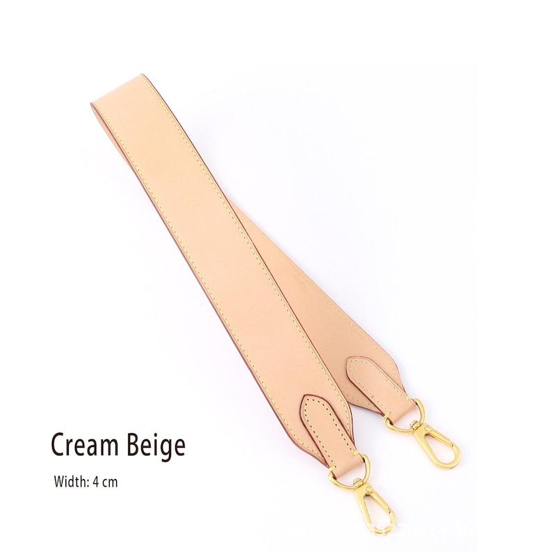 May include: Cream beige purse strap with gold-colored metal clasps. The strap is 4 cm wide and made of a smooth, light-colored material. The text "Cream Beige" is displayed on the image.