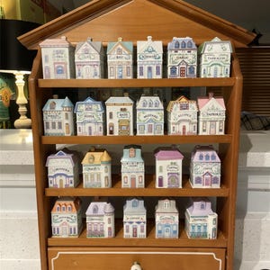 Pode incluir: Uma caneca de cerâmica branca com uma alça preta e o texto "But First, Coffee" em preto, com uma fonte manuscrita. A caneca está sobre uma superfície branca.