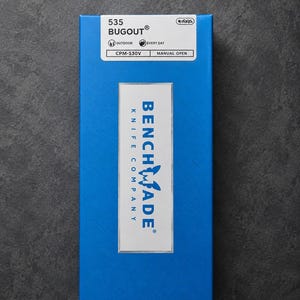May include: A blue rectangular box with white text and a logo. The box reads "535 BUGOUT" and "BENCHMADE KNIFE COMPANY". Additional text includes "OUTDOOR", "EVERY DAY", "CPM-S30V", and "MANUAL OPEN".