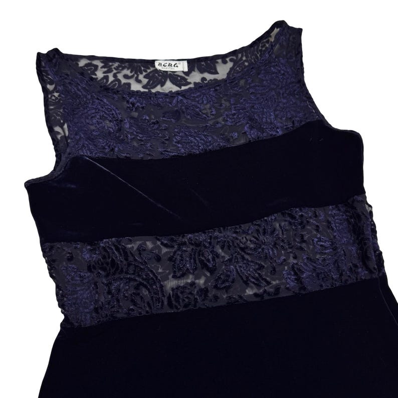 May include: A navy blue sleeveless dress with a velvet bodice and lace detailing. The dress has a sheer lace overlay at the neckline and a wide lace band across the midsection. The brand name "BCBG" is visible on a tag.