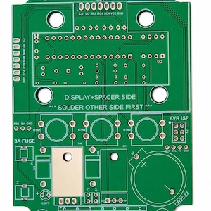 May include: A green printed circuit board for a Picapot irrigation controller, version HT328.3.2. The board features labeled mounting holes, solder pads for buttons, a 3A fuse slot, a CR2032 battery holder area, and text reading DISPLAY+SPACER SIDE.