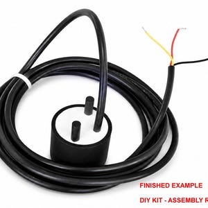May include: A black cylindrical sensor with a white top featuring two protruding black pins, connected to a long black cable. The cable ends in three exposed wires colored yellow, red, and black. Text reads: FINISHED EXAMPLE DIY KIT - ASSEMBLY REQUIRED.