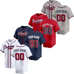 Pode incluir: Uma caneca de cerâmica branca com uma alça preta e o texto "But First, Coffee" em negrito preto. A caneca está sobre um fundo desfocado, sugerindo um ambiente acolhedor.