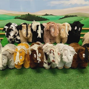 May include: A selection of soft toy horses in diverse colours, such as black, white, brown, tan, and orange. Each toy has a fluffy mane and tail, with some having patterned coats. The toys are displayed on a green surface.