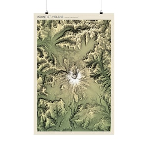 May include: A vertical topographic map print of Mount St. Helens featuring a detailed relief of the volcanic crater and surrounding terrain in shades of sage green, tan, and white. The text MOUNT ST. HELENS is printed at the top in black.