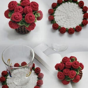 May include: Crocheted coasters and decorative flower arrangements. The coasters are white with a border of red roses and green leaves. The flower arrangements are red roses in a brown basket. Handmade home decor.