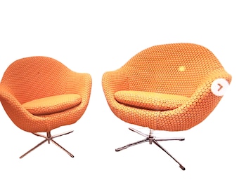 May include: Two orange swivel chairs with a textured fabric. The chairs have a chrome base with five spokes.