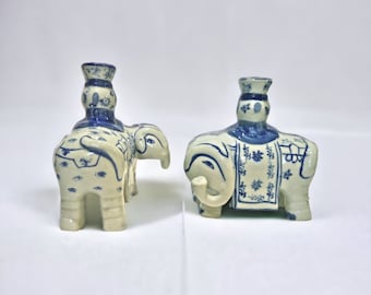 May include: Two blue and white ceramic elephant candle holders. Each elephant has a blue and white patterned saddle and a blue and white candlestick on its back.