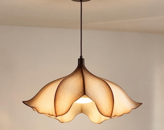 Puede incluir: Una lámpara colgante con una pantalla en forma de flor abierta con seis pétalos curvos y translúcidos. La pantalla presenta un degradado de color beige claro a bordes marrón oscuro, suspendida por un cable fino desde un soporte circular.