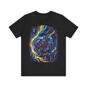 Puede incluir: Camiseta negra con una ilustración colorida de un minero barbudo en una cueva. El minero sostiene un pico y lleva un casco con una luz. La cueva tiene elementos brillantes azules, amarillos y morados.