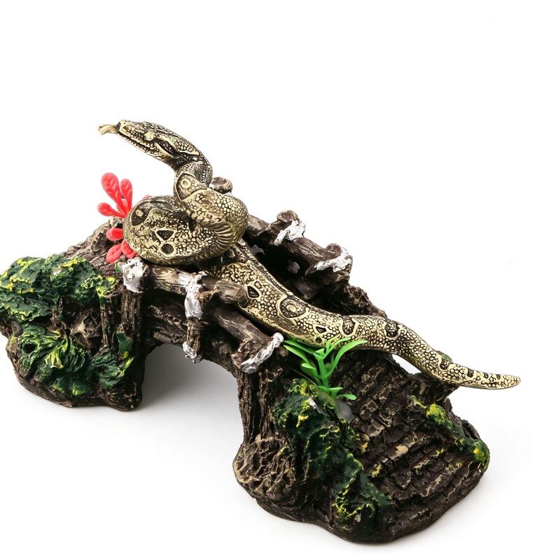 Op de afbeelding: Gedetailleerde decoratie voor reptielenhabitat met een opgerolde slang met een getextureerd, patroonlichaam. De slang rust op een gedetailleerde, faux-houten brug met groene en rode accenten, ontworpen voor een terrarium of aquarium.