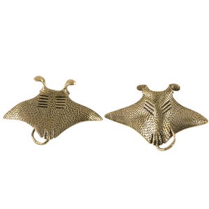 May include: Two bronze-coloured manta ray sculptures. Each sculpture has a textured surface, detailed gills, and a loop at the bottom. The manta rays are displayed against a white background.